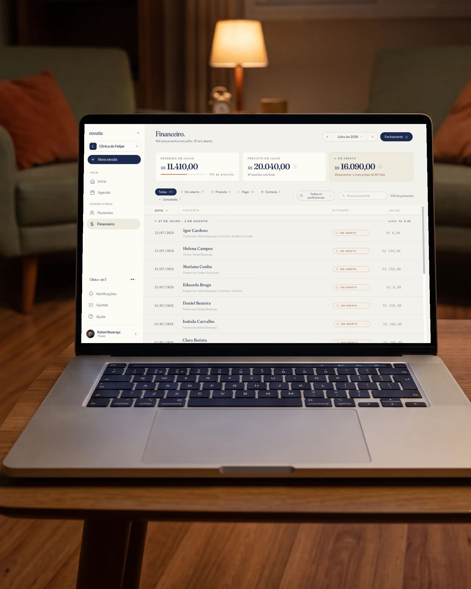 Notebook aberto na mesa do consultório ao anoitecer, mostrando o financeiro do mês